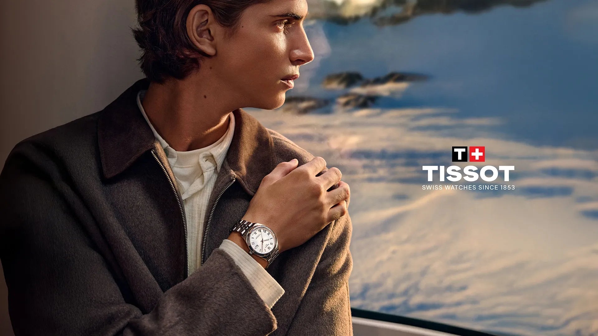 Man wearing a Tissot watch with a scenic background