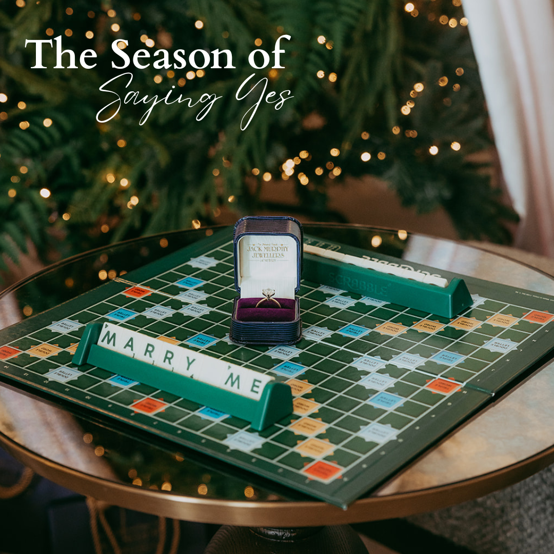 Scrabble board with 'MARRY ME' and ring box, Christmas tree in background